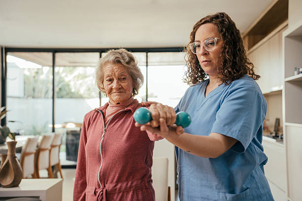 istock Elderly patient undergoing physical therapy with dumbbells - home consultation 2232288775