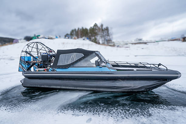 istock A modern hovercraft glides effortlessly over a frozen lake, showcasing its sleek design. The surrounding landscape is a serene winter scene, with snow-covered hills in the background and scattered 2232292388