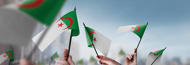 istock Algeria flags in their hands on a blurred urban background 2232294830