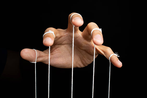istock male puppeteer hand with strings isolated on black background. manipulation or controlling concept 2232298963