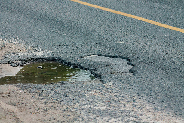 istock Old asphalt road with dangerously damaged asphalt that has potholes dangerous for the transit of motor vehicles 2232300633