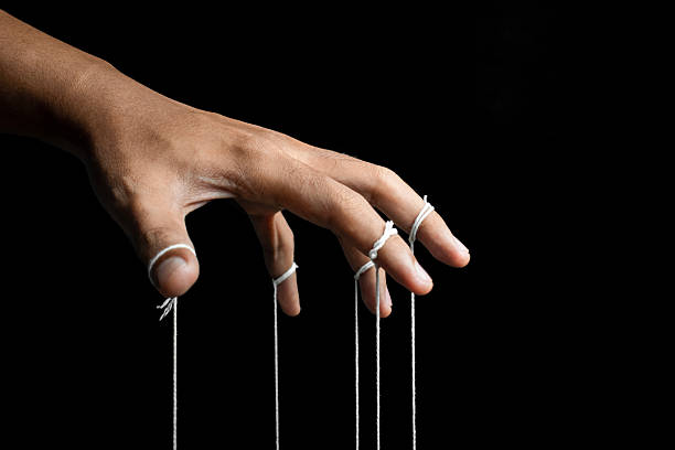 istock male puppeteer hand with strings isolated on black background. manipulation or controlling concept 2232301326