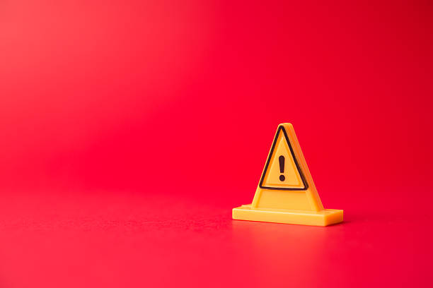 Yellow triangle warning sign (or exclamation) on red background with copy space. Abstract warning sign, caution, alert symbol, emergency concept.