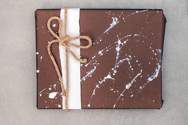 a gift wrapped in brown and decorated with white paint splatter. A rustic tie with thick hessian type string gives a rustic and manly feel