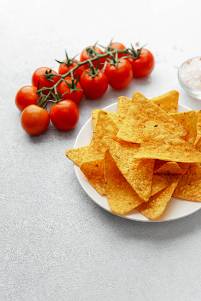 istock Plate of nacho chips with tomatoes, salt and dip on white background 2232312603