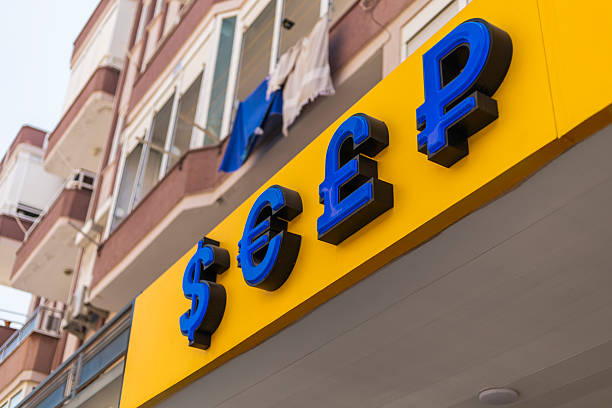 istock A storefront dedicated to currency exchange features vibrant blue and yellow signs displaying different currency symbols. Nearby residential buildings are visible 2232313929