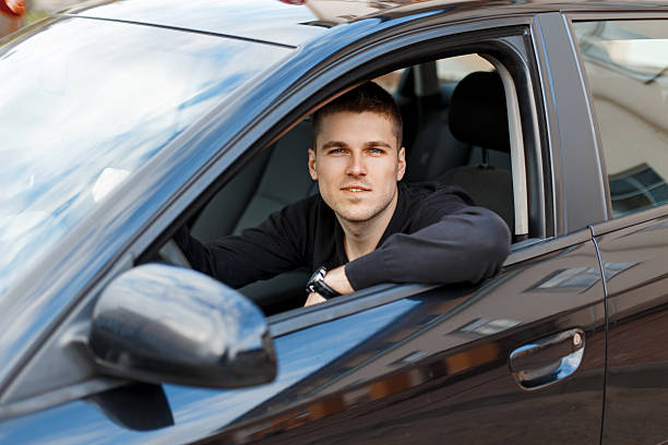 istock Handsome young male driver in a black car 2232319640