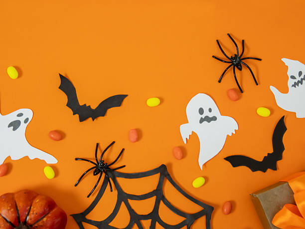 istock A gift box with orange bows, small pumpkins and decorations on an orange background create a festive mood for Halloween 2232319647