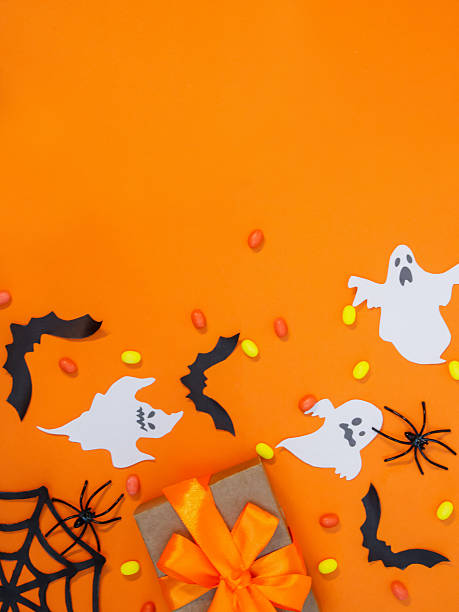 istock A gift box with orange bows, small pumpkins and decorations on an orange background create a festive mood for Halloween 2232319928