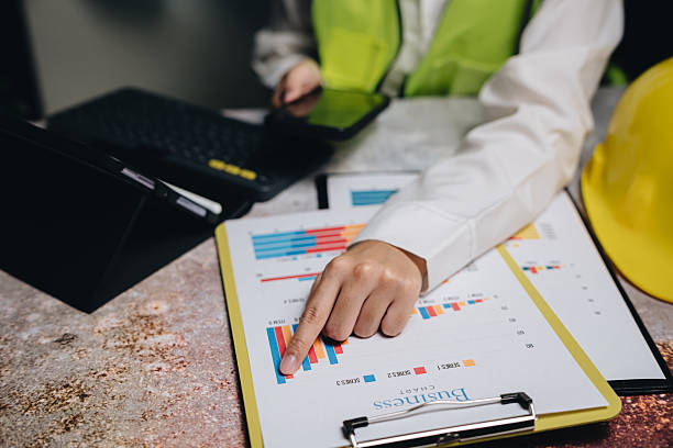 istock Business Professional Analyzing Charts and Graphs on Clipboard with Construction Helmet in Modern Office 2232324681