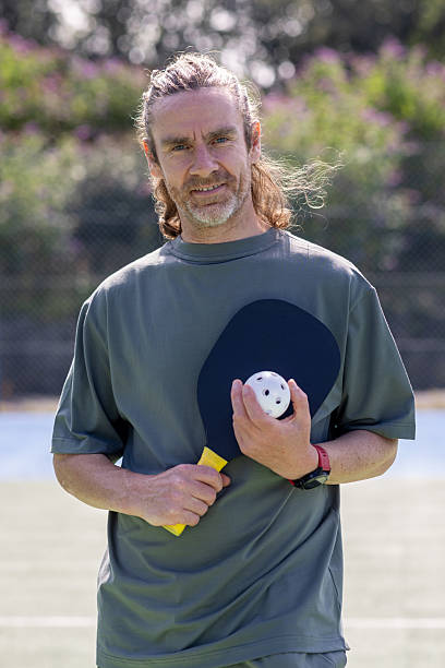 istock Man Smiling While Holding Pickleball Equipment 2232324883