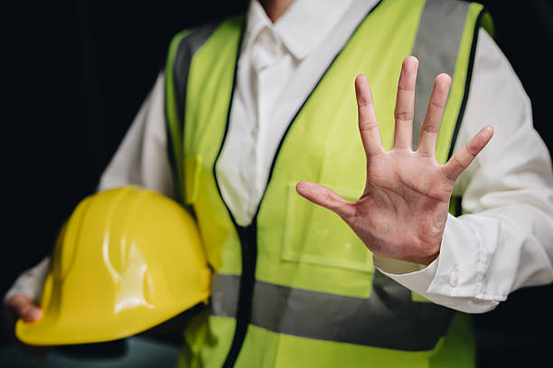 istock Construction Worker Wearing Safety Vest Stopping Gesture with Hard Hat in Work Environment 2232324997