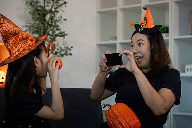 istock Halloween Fun. Capturing joyful moments with a smartphone during pumpkin festivities. 2232327449