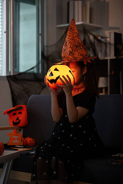 istock Halloween Celebration. Child in a witch hat holding a pumpkin lantern, ready for fun. 2232327587