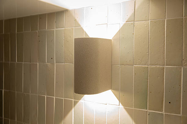 Modern ceramic wall sconce casting dual light on tiled wall for ambiance