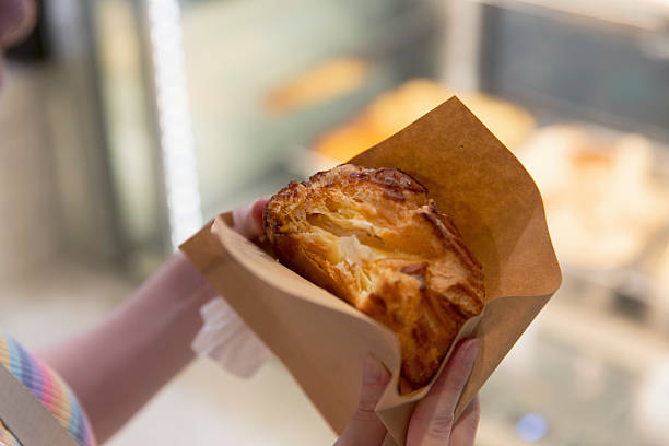 istock Vanilla ice cream puff pastry held in hands in front of bakery counter 2232328231