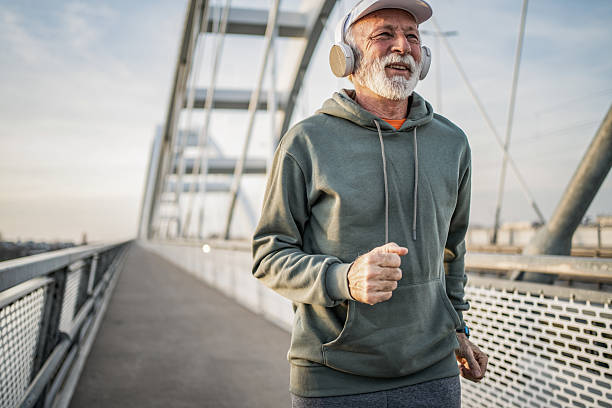 istock Senior man jogging on a bridge while listening to music 2232329095