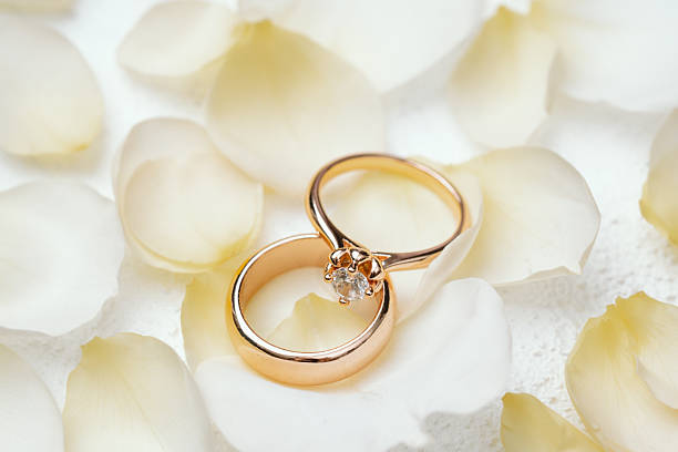 istock Wedding and engagement rings on white petals background 2232330037