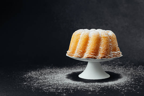 Golden bundt cake on white stand with dark stone background