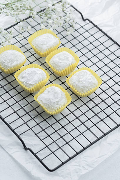 istock Delicate white confections on wire rack with flowers in soft lighting 2232330243