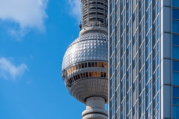 Germany, Berlin, Alexanderplatz, August 24, 2025 - The Berlin TV tower behind a modern skyscraper