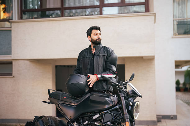 istock Man standing next to motorcycle holding helmet 2232332186