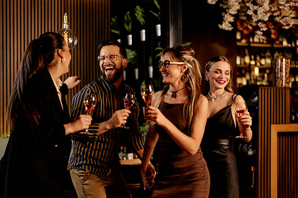istock Friends Enjoying a Night Out Laughing and Drinking Wine Together 2232333206