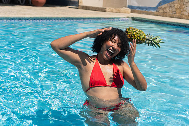 istock Young woman having fun with pineapple in swimming pool 2232333661