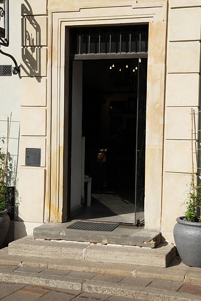 istock Sunlit storefront entrance;  beige stone facade, dark door,  interior dimly visible.  Elegant, inviting mood. 2232334182