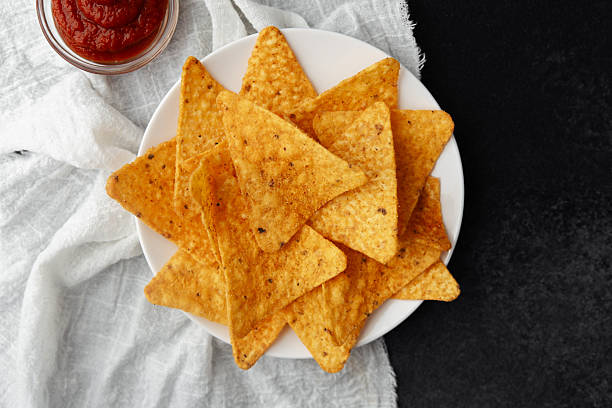 istock Nacho chips on plate with tomato sauce on white cloth and black background 2232335149