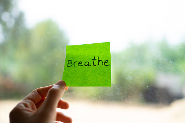 istock Hand holding a green sticky note with breathe written on it 2232336541
