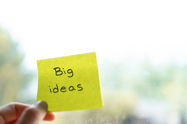 istock Hand holding adhesive note with big ideas writing on blurry background 2232336555
