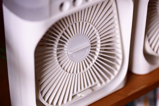 istock Two white fans sit atop a wooden shelf, ready for use 2232336847