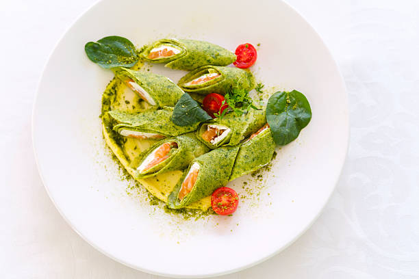 Delicious spinach wraps filled with smoked salmon on a white plate