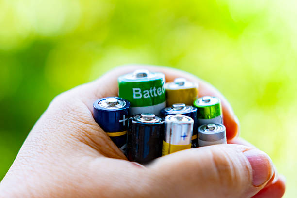 hand holding collection discarded batteries, Environmental consciousness, proper battery recycling and disposal, emphasizing issue electronic waste, discarded power cells, Green initiative