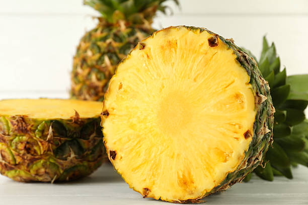 istock Cut fresh ripe pineapple on white wooden table, closeup 2232343924