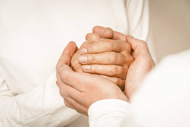 Two hands interlocked in a gentle embrace signify warmth and compassion for an elderly mother. This intimate moment reflects unwavering support and affection at home