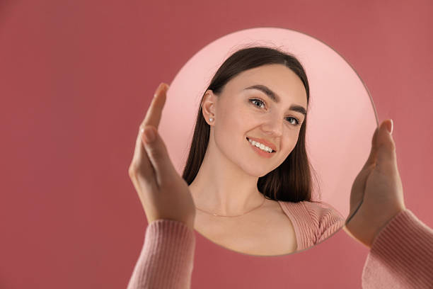 istock Woman holding round mirror on pink background, closeup. Space for text 2232345971