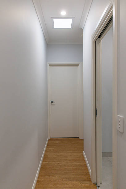 istock Hallway with wood floor and ceiling light leading to white door interior 2232346034