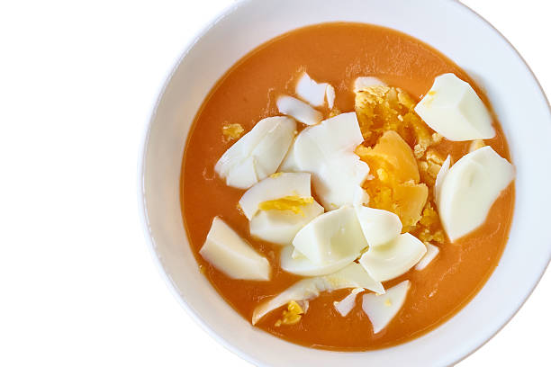 Traditional spanish cold tomato soup, known as salmorejo, featuring garnished chopped hard-boiled eggs, served in a white bowl