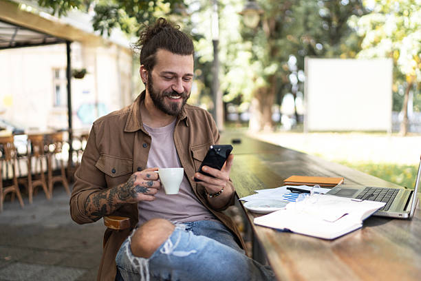 istock Freelancer enjoying coffee and checking smartphone at outdoor cafe 2232350183