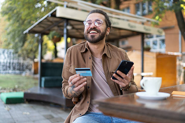 istock Happy young man making online payment using credit card and smartphone 2232350517