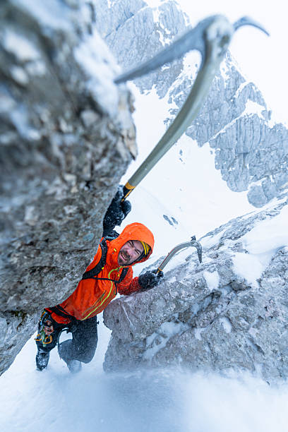 istock Mountaineer In Bright Orange Jacket Climbing Steep Ice Wall With Technical Tools In Winter Alps 2232352160