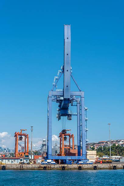istock Large blue crane operates alongside docks in a bustling port under a clear sky 2232352486