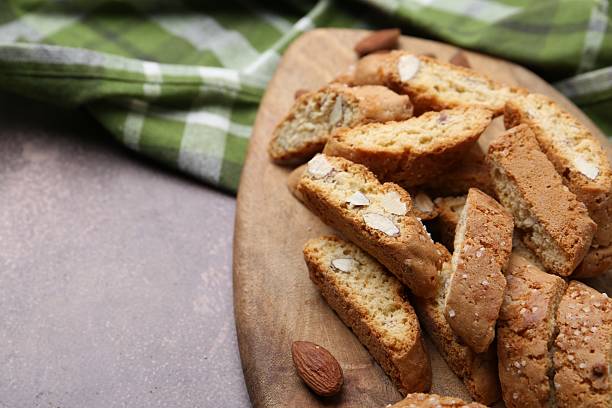 istock Tasty almond biscuits (Cantuccini) and nuts on brown textured table, closeup. Space for text 2232353032