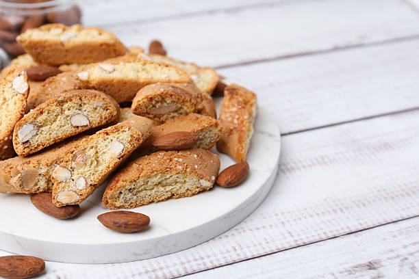 istock Tasty almond biscuits (Cantuccini) and nuts on light wooden table, closeup. Space for text 2232353134