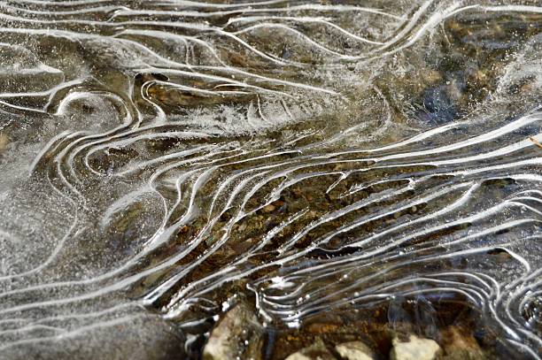 Water freezes in delicate, graceful patterns in an icy river during the winter season in the Berkshires, Massachusetts