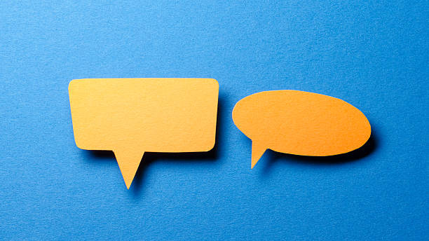 istock Orange blank cut out paper speech bubbles with copy space for text on blue background, flat lay top view discussion conversation concept 2232355341