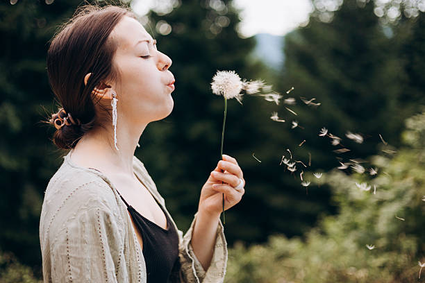 istock Young woman blowing fluffy dandelion seeds in summer forest, copy space. 2232355606