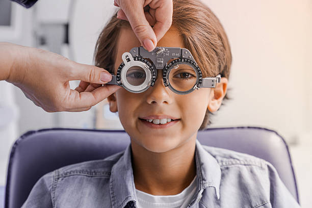 istock Young boy with phoropter during sight testing eye examinations in ophthalmological clinic. Optometry concept. Selecting eyesight frame lenses for goggles glasses 2232356693